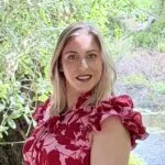 Claudia Landry, Owner and Clinical therapist, with a pink/red flower blouse and a canal with water and trees on the background